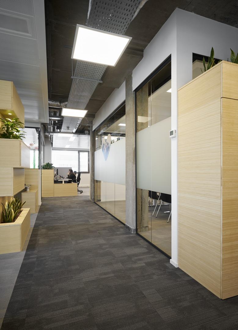 Seamless glass partitions wall that divides the conference room from the larger office